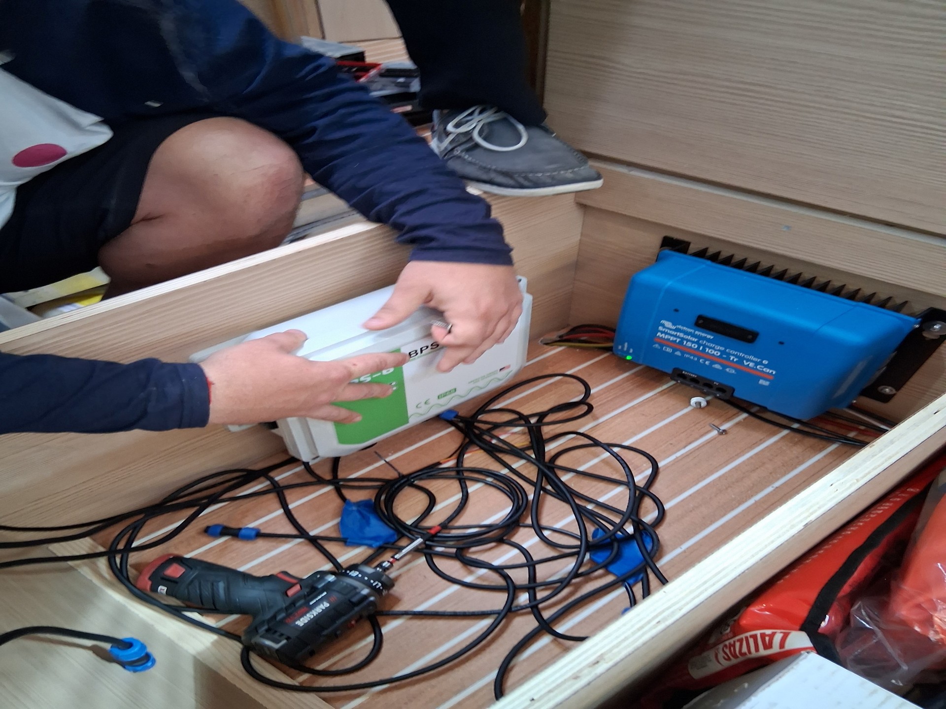 Técnico fija la caja de control BPS junto al regulador de carga a bordo